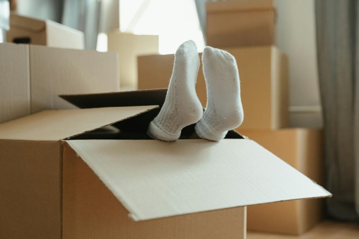 A playful moment during moving into a new home, with feet in a box and cardboard surroundings.