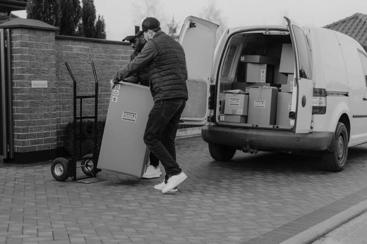 Two men unloading fragile packages from a delivery van, showcasing teamwork in logistics.