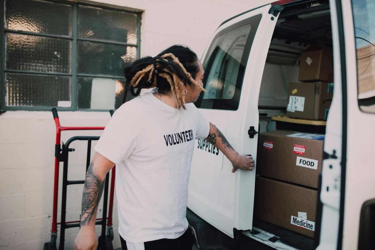 Volunteer loading boxes labeled food and medicine into van, supporting community donations.