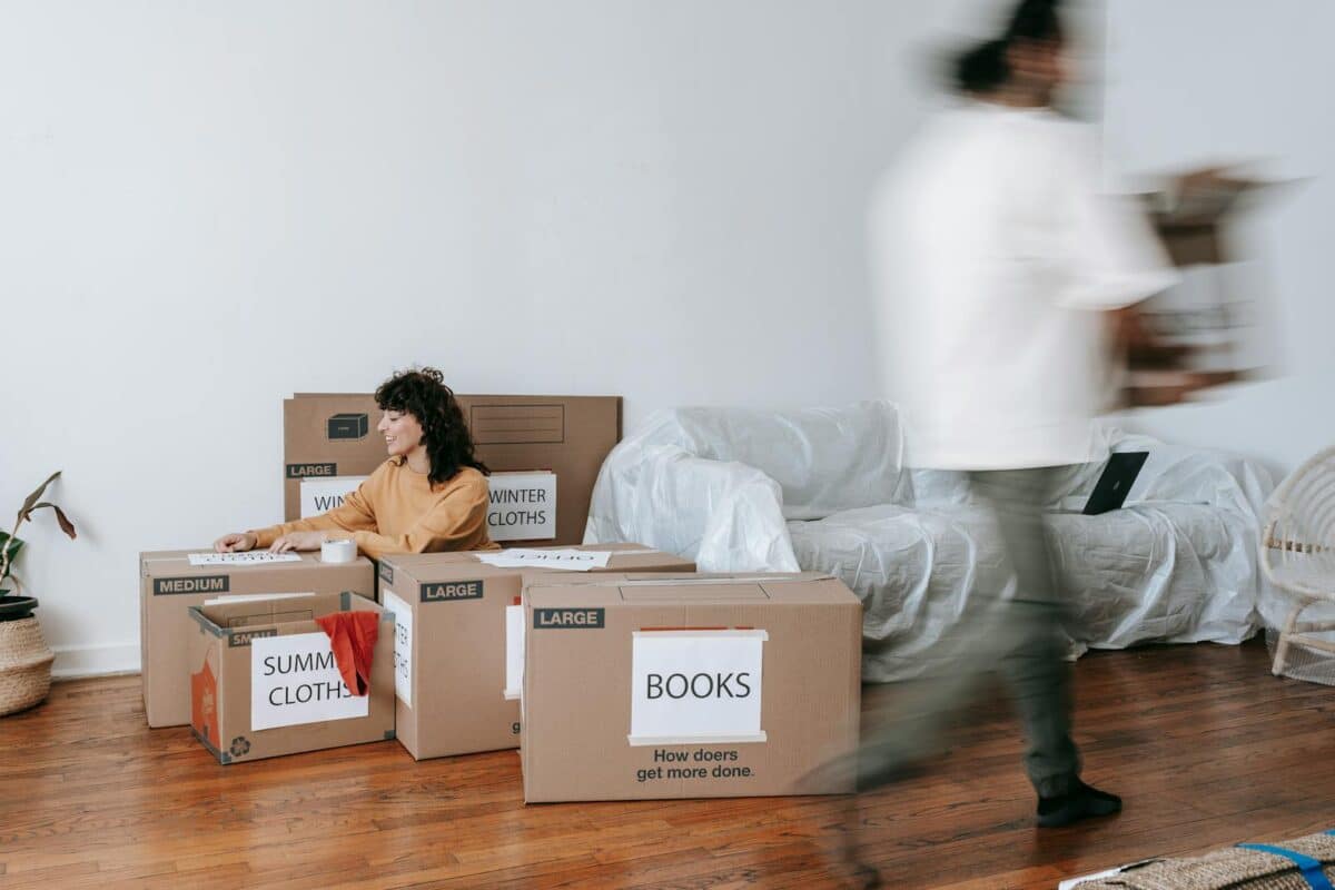 A couple packing labeled boxes in a minimalist living room, preparing for moving day.